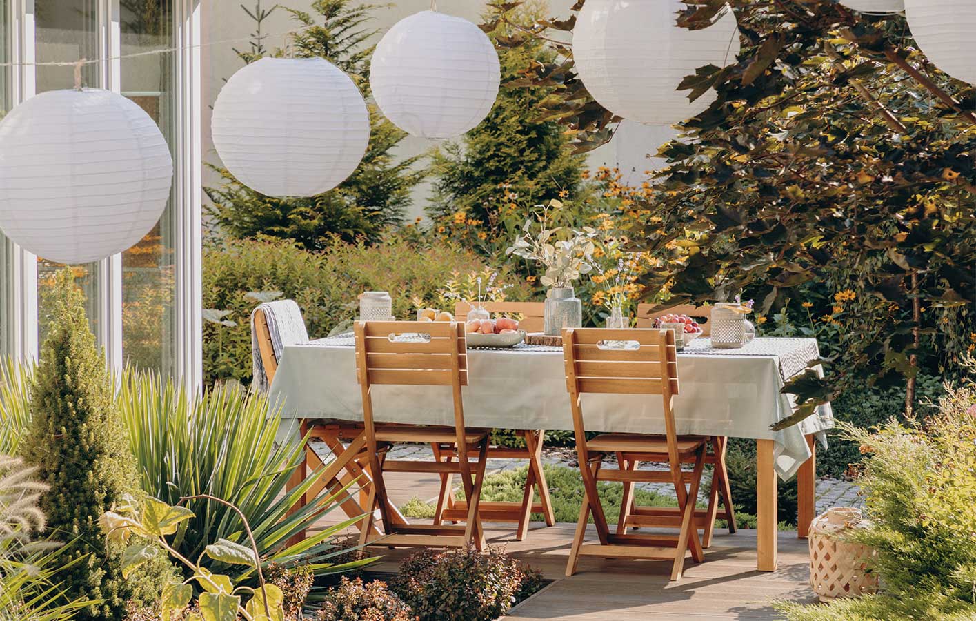Terrasse im Sommer mit einem gedeckten Tisch und Lampions